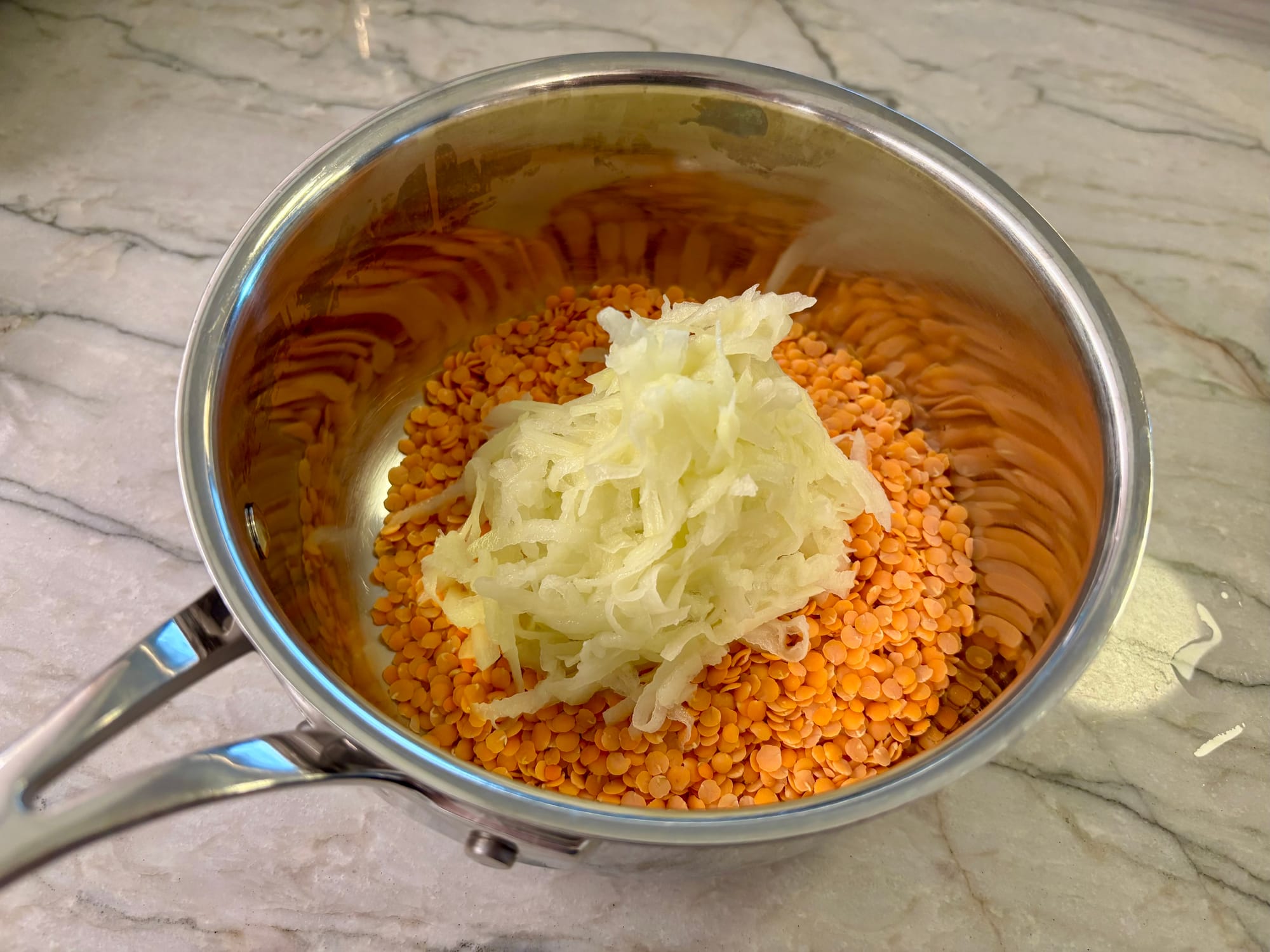 Red lentils and shredded potatoes in a pot.